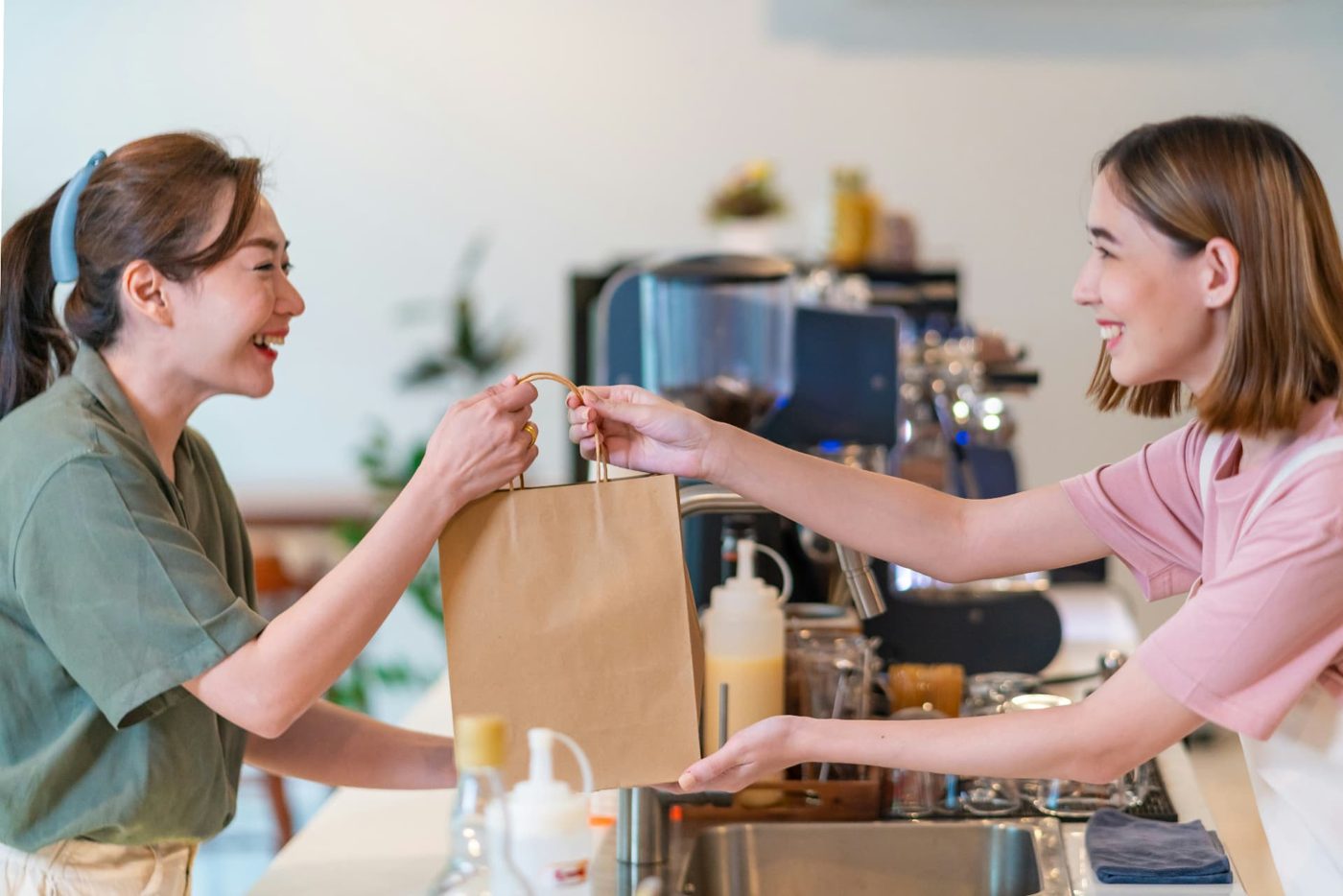 Café worker handing a customer a paper takeaway bag